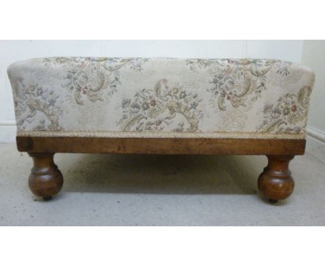 A late Victorian mahogany framed box stool, upholstered in braided, floral patterned fabric, raised on bulbous feet and rolle