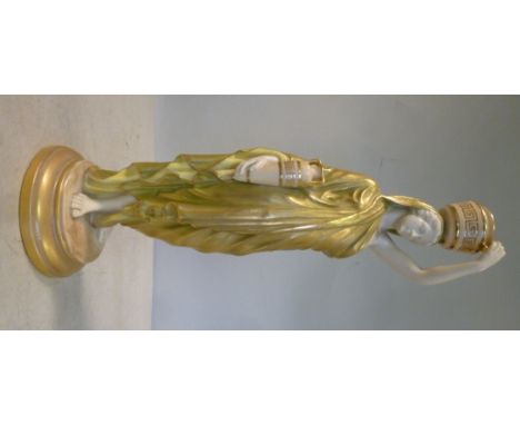 A Royal Worcester gilded satin green and yellow glazed china figure, a standing, robed young woman, holding a pot on her head