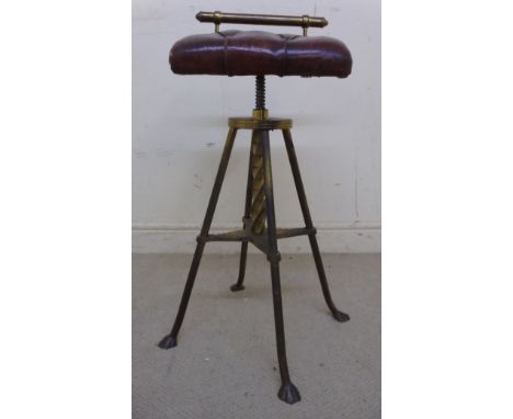 A late 19thC brass framed, rotating, height adjustable organ stool, having a tubular back and a red buttoned hide upholstered