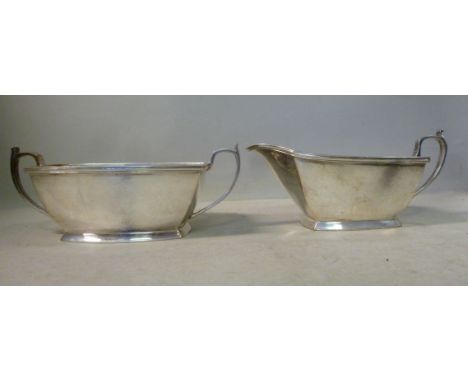 A silver cream jug of panelled form, having flared sides and an applied wire rim, a cast loop handle and a matching twin hand