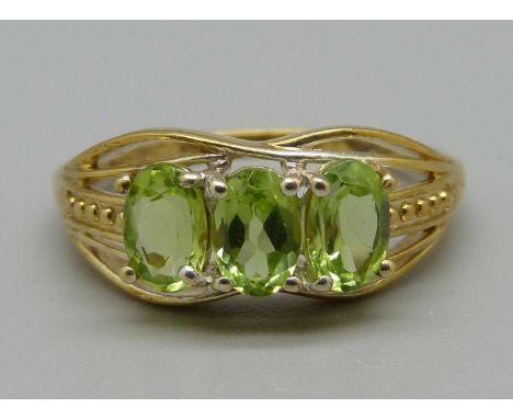 A silver-gilt peridot trilogy ring, O 