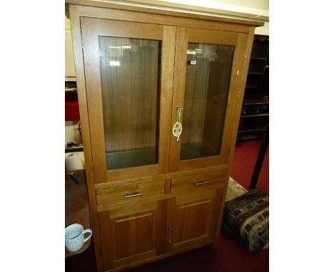 A contemporary light oak side cabinet, having twin glazed upper doors with two adjustable glass shelves, width 107cm