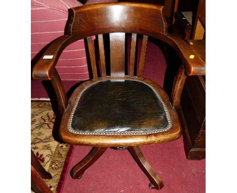 A 1930s oak slat back tub swivel desk chair, having a green leather studded pad seat on roller castors, width 55.5cmCondition