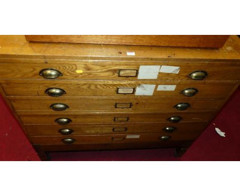 A 1930s light oak six drawer plan chest, comprised of two sections, having panelled sides and raised on square block supports