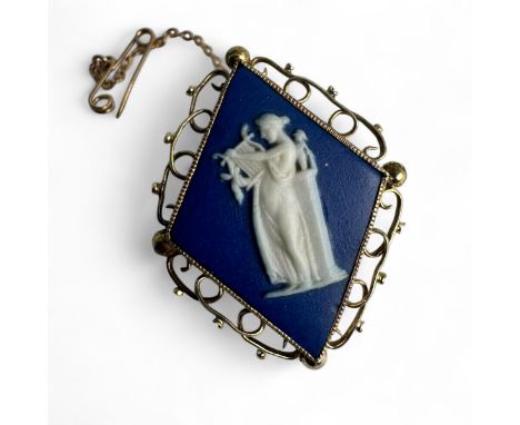 A Wedgewood Jasperware cameo brooch in a yellow precious metal mount. Featuring a kite shaped plaque of a woman playing a lyr