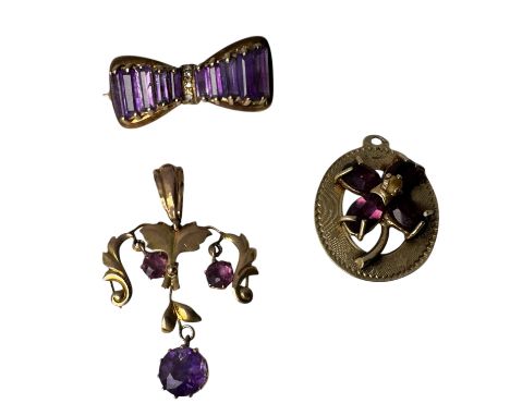 A collection of amethyst and purple paste jewellery. Comprising a 9k stamped mid century bow brooch; a purple paste set flowe