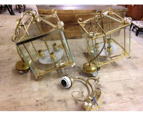 A pair of brass and glass ceiling lights with a brass wall light.