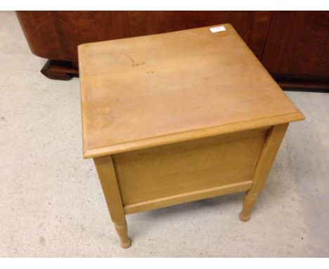 A light wood commode with ceramic chamber pot.