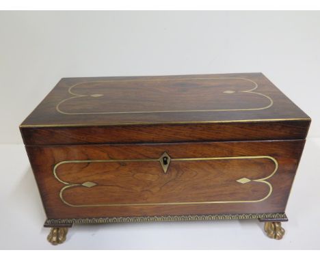 A large Regency rosewood and brass inlaid tea caddy with ormulu beading and gilded paw feet, inside two lidded compartments, 