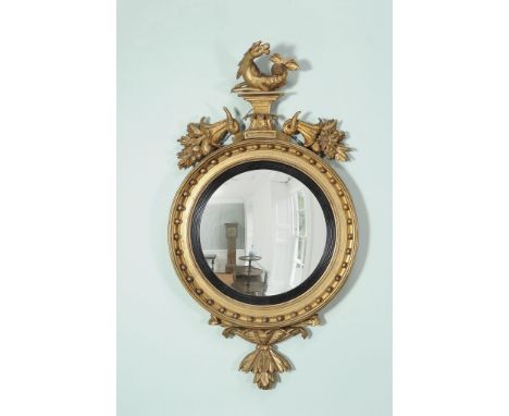 A George III giltwood circular convex wall mirror  , circa 1810, the plate and reeded sight edge surmounted by a model of a 
