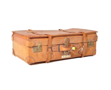 An early 20th century tan leather suitcase / trunk case having stitched leather mounts to corners and luggage label to surfac
