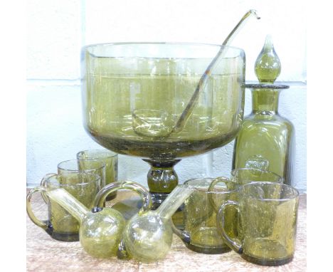 A green art glass decanter with six matching cups, ladle, punch bowl and double spout pourer