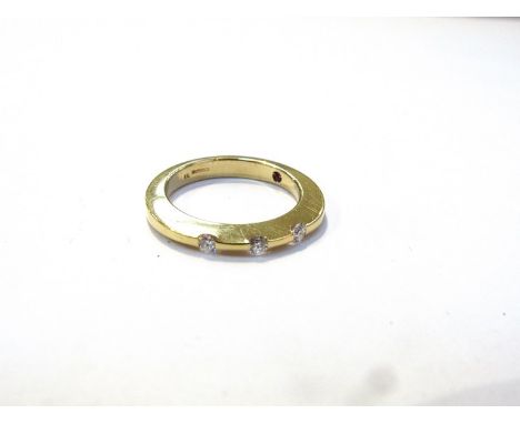An 18ct gold designer ring set with three bright cut diamonds, shank set with ruby, size N, 5.1g