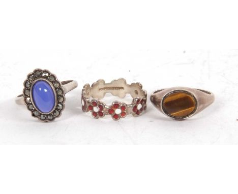 Three silver rings: a red and white enamel 'daisy' ring stamped 'silver', size P; a silver tigers eye ring, size P; and a blu
