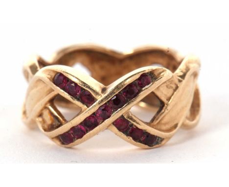 A 14k ruby crossover ring, the two crossover strands set to centre with small round rubies forming a cross, the textured stra