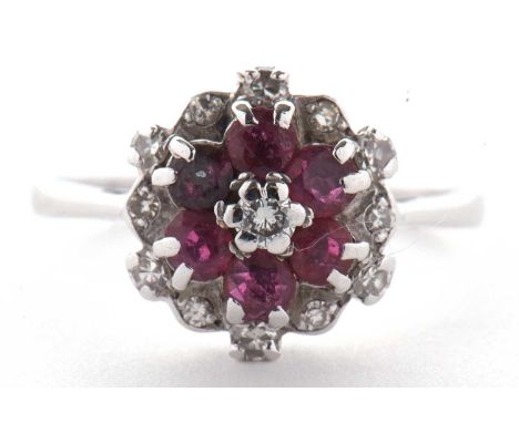 An 18ct ruby and diamond cluster ring, the central small round diamond, surrounded by round rubies and a further outer ring o