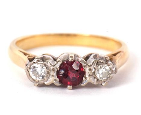 A three stone ruby and diamond ring, the central round ruby set to either side with an illusion mounted diamond, all set in w