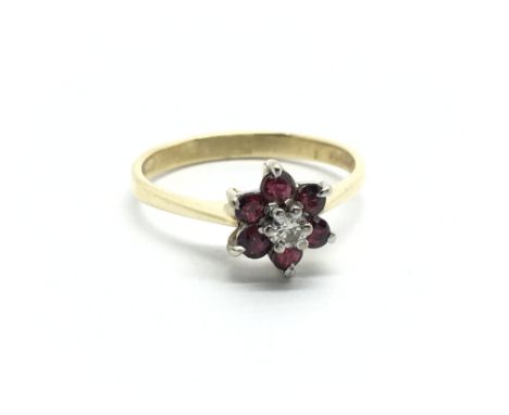 An 18ct gold ring set with a central diamond surrounded by rubies in the form of a flowerhead, approx 2.4g and approx size L.