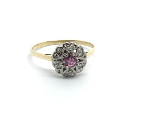 An unmarked gold ring set with a central ruby surrounded by diamonds in the form of a flowerhead, approx 2g and approx size M