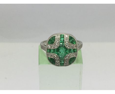 An Art Deco style platinum ring set with emeralds and diamonds in a stylish panel design, approx 4.3g and approx size M-N.