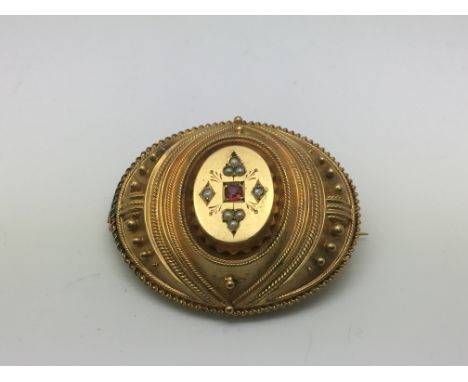 A yellow metal mourning brooch set with seed pearls and a central ruby.