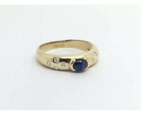 An 18ct gold ring set with a central cabochon sapphire and eight small diamonds, approx 3g and approx size O.