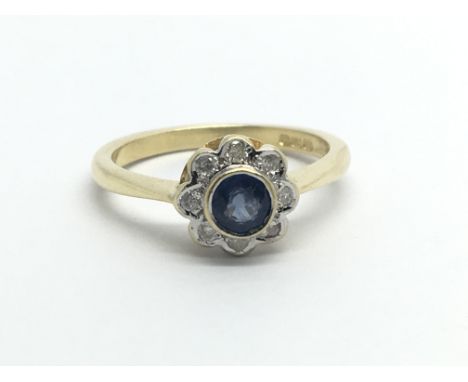 An 18ct gold ring set with a central sapphire and surrounded by eight diamonds in a flowerhead setting, approx 3.7g and appro