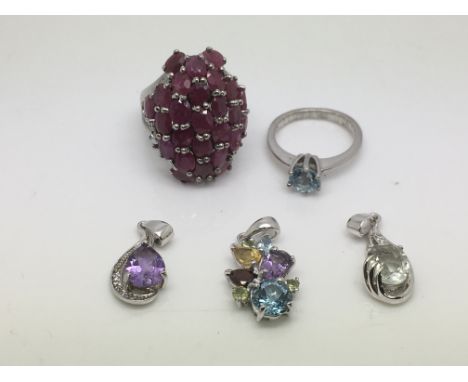 Three multicolour gemstone silver pendants, a silver solitaire blue topaz ring and a silver ring set with rubies.