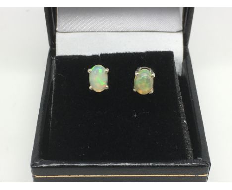 A boxed pair of white Ethiopian opal ear studs set in silver.