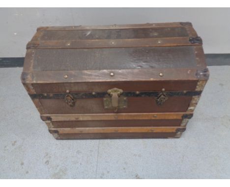 An antique wooden bound dome topped shipping trunk 