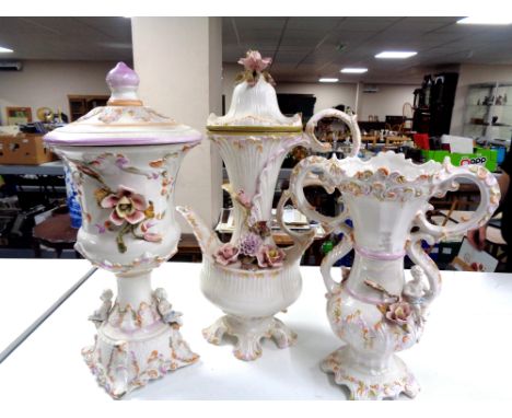 A three piece glazed pottery flower encrusted set to include lidded vase, twin handled vase and oversized teapot 