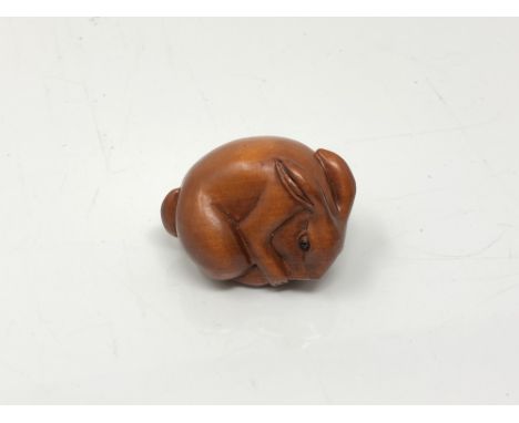 A carved Chinese hardwood netsuke - Rabbit feeding