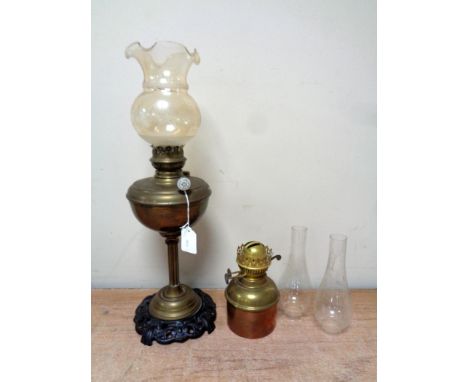 An antique German brass oil lamp with glass shade on cast iron base together with a further brass and copper oil lamp, togeth