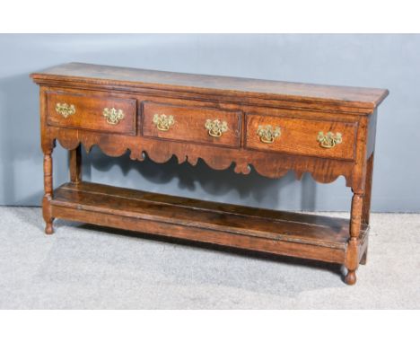 An 18th Century Oak Dresser Base, the two plank top with chamfered edge, fitted three frieze drawers with shaped apron on tur