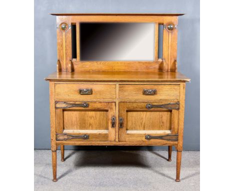 A Victorian Oak Sideboard of Liberty's Arts and Crafts Design, the back fitted shelf above bevelled mirror panel, flanked by 