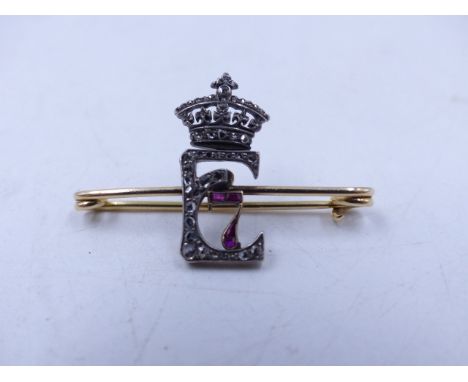 A DIAMOND AND RUBY SET YELLOW METAL PIN, FORMED IN THE LETTER E ENTWINED WITH A NUMBER 7, A GIFT FOR THE WIFE OF COLONEL WILF