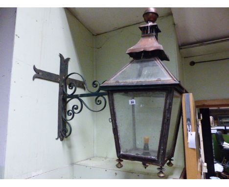 AN ANTIQUE COPPER OUTSIDE LANTERN ON WROUGHT IRON WALL BRACKET.   H.90cms.