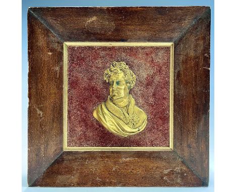 A gilt metal portrait bust of George IV, looking slightly to dexter, on a velvet mount and walnut frame, 27.5cm square.Proven