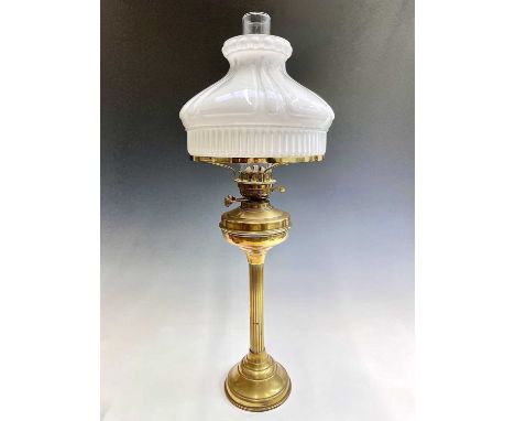 A brass oil lamp, circa 1900, with fluted opaque glass shade on a fluted column support. Height 76cm.