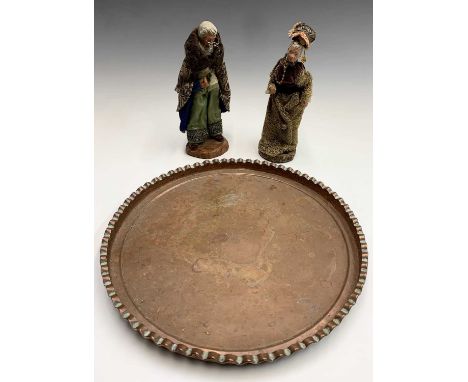 A pair of terracotta figures dressed in handmade clothes, height 26cm, together with a circular copper tray with pie crust ri