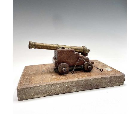 A model cannon, with brass barrel, on a mahogany carriage and base, width 28cm.Provenance:Michael Trethewey. A Gentleman of T