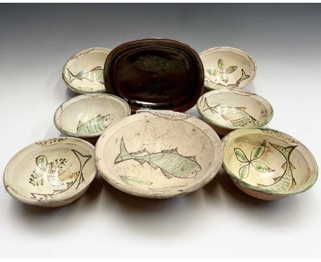 A Winchcombe pottery tenmoko glazed dish with resist decoration of two fish, width 26cm; together with a slipware fish decora
