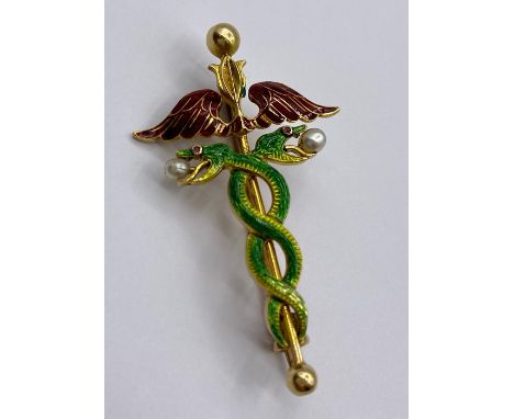 An 18ct gold enamel brooch in the style of the hypocratic oath with intertwined serpents, wings with two seed pearls. (7g) 4.