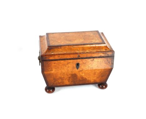 An early 19th Century burr yew wood and cross banded sarcophagus shaped tea caddy, the lid inlaid with a musical panel of "Ho