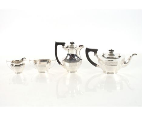 A matched four piece silver tea set, of panelled form decorated with a foliate engraved band, black wood handles and lifts to