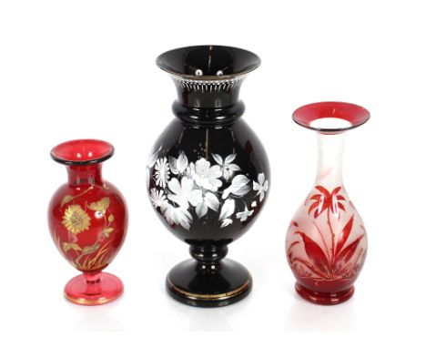 A Victorian black opaque glass vase, with white enamel floral decoration; a ruby glass baluster vase with gilt foliate decora