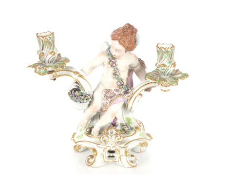 A late 19th Century continental porcelain Meissen type two branch candelabra, supported by a winged Putti, 29cm high&nbsp;