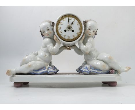 A Meissen porcelain cased mantel clock, 'Uhr Von Zwei Putten Getragen, modelled by Paul Scheurich, the striking drum movement