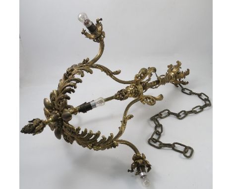 A brass hanging light fitting, decorated with leaves and scrolls, with six light, having three shell moulded frosted glass sh