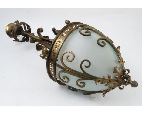 A brass hanging light fitting, the column decorated with plain scrolls and scrolling leaves, the shade with pierced brass ban